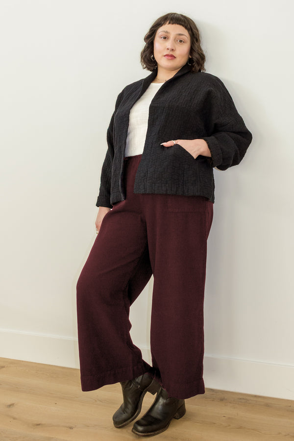 Atlas Pant in Burgundy on model leaning against white wall