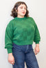 Model wearing Anya Checkerboard Sweater in Fern and denim jeans, in front of white background