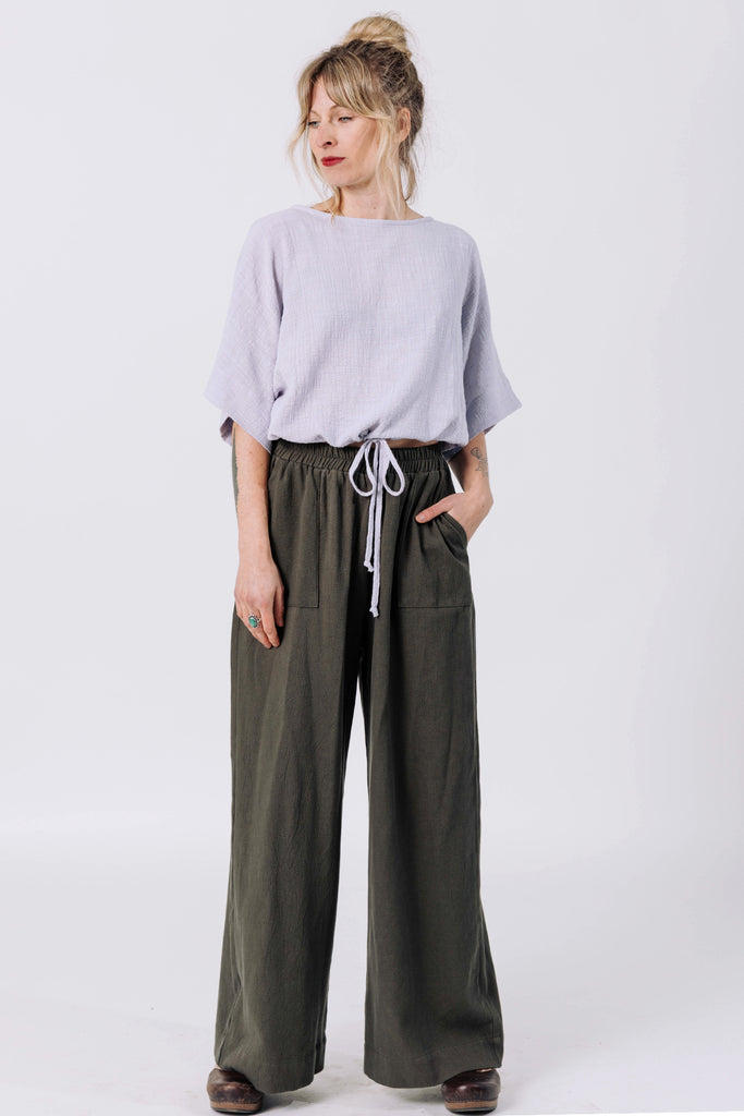 Front view of model wearing Ayana Top in Mist and Atlas Pant in Mud, standing with hands in pants pockets in front of white background
