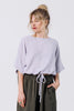 Front view of model wearing Ayana Top in Mist and Atlas Pant in Mud, standing with one hand in pant pocket in front of white wall