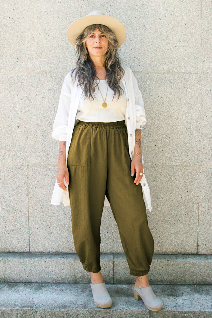 Cadence Pant in Fennel paired with Workshirt in Natural on model standing in front of stone background