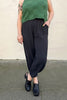 Model wearing Zoe Top in Fern and Cadence Pant in Faded Black/Black Stripe in front of white wall