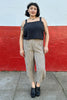Model wearing Bianca Top in Black and Cadence Pant in Oat/Black Stripe in front of white and red painted wall