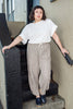Model wearing Ayana Top in White and Cadence Pant in Oat Stripe, standing with in black and tan stair entryway