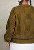 Back view of model wearing Anya Checkerboard Sweater in Fennel in front of white background