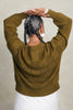 Back view of model wearing Anya Checkerboard Sweater In Fennel and Atlas Pant in White in front of white background