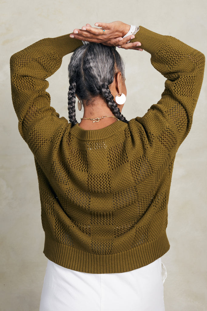 Back view of model wearing Anya Checkerboard Sweater In Fennel and Atlas Pant in White in front of white background
