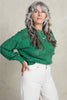 Model wearing Anya Checkerboard Sweater In Fern and white jeans in front of white background