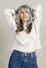 Model wearing Anya Checkerboard Sweater in Biscuit, with arms raised above head, in front of white background