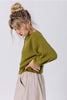 Side view of model with arms over head wearing Clove Sweater in Fennel and Fawn Skirt in Oat in front of white background