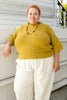 Model wearing Cody Waffle Tee in Dijon and Cadence Pants in White, leaning against a white buidling