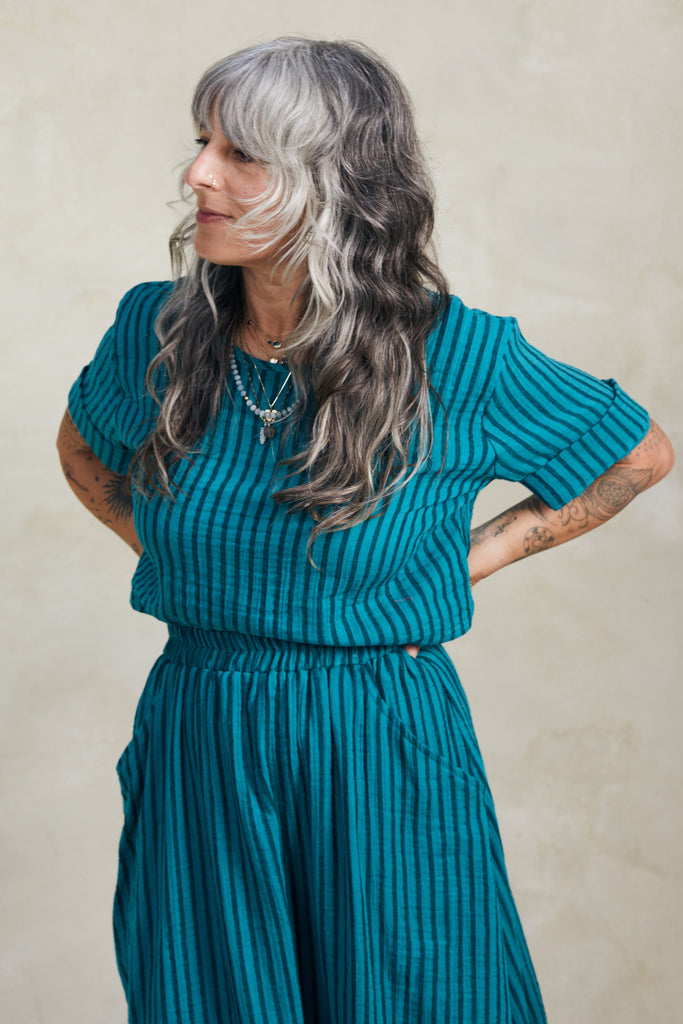 Noa Stripe Top in Ocean, paired with Fawn Stripe Skirt in Ocean, on model standing with hands on hips in front of white background
