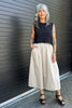 Model wearing Minnie Tank in Black and Fawn Poplin Skirt in Oat in front of black garage door