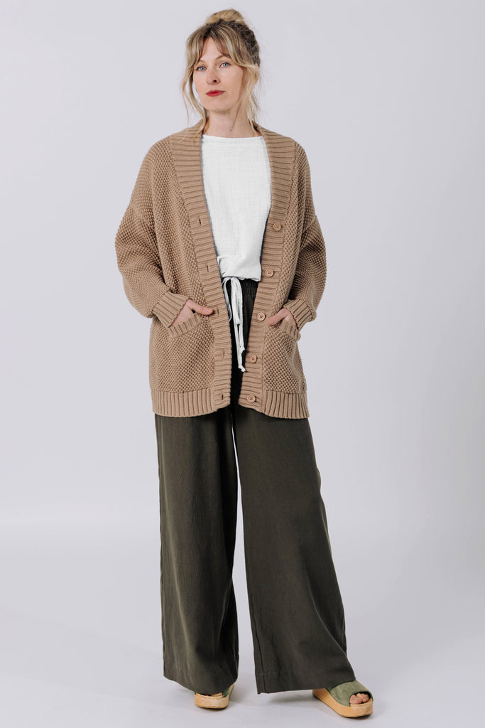 Front view of model wearing Frankie Cardigan in Tan , Ayana Top in White, and Atlas Pant in Mud in front of white background