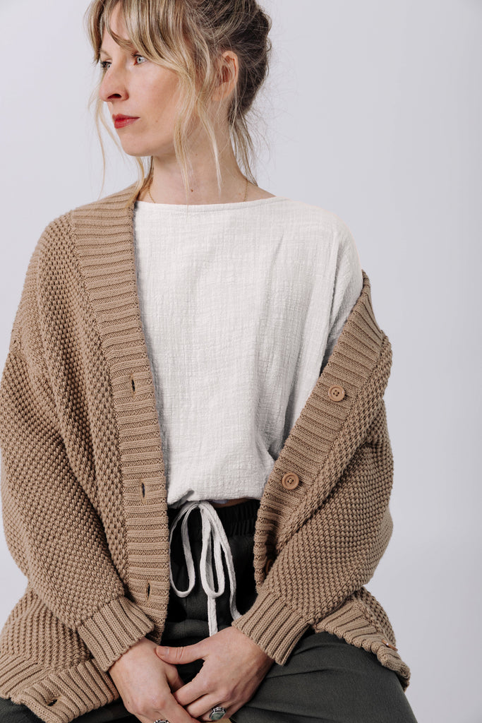 Front view of model wearing Frankie Cardigan in Tan , Ayana Top in White, and Atlas Pant in Mud in front of white background