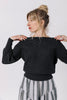 Front view of model wearing Ivy Sweater in Black and Jessie Stripe Skirt in Oyster, standing with hands on shoulders in front of white background