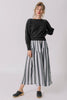 Front view of model wearing Ivy Sweater in Black and Jessie Stripe Skirt in Oyster, with one hand on hip, standing in front of white background
