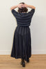 Back view of odel wearing Izzy Top and Jessie Skirt set in Faded Black Stripe standing in front of white wall