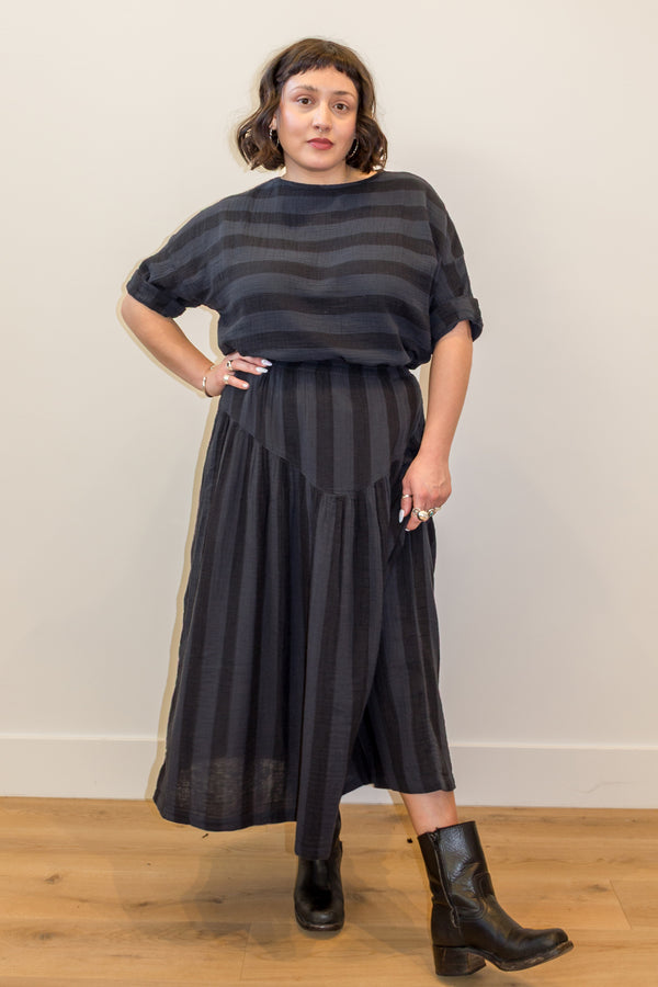 Model wearing Izzy Top and Jessie Skirt set in Faded Black Stripe standing with a hand on hip in front of white wall
