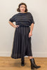 Model wearing Izzy Top and Jessie Skirt set in Faded Black Stripe standing with a hand on hip in front of white wall