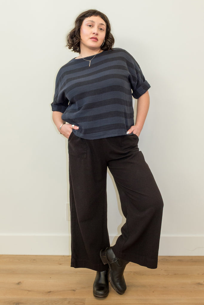 Front view of Atlas Pant in Black on model, paired with Izzy Stripe Top in Black, in front of white wall