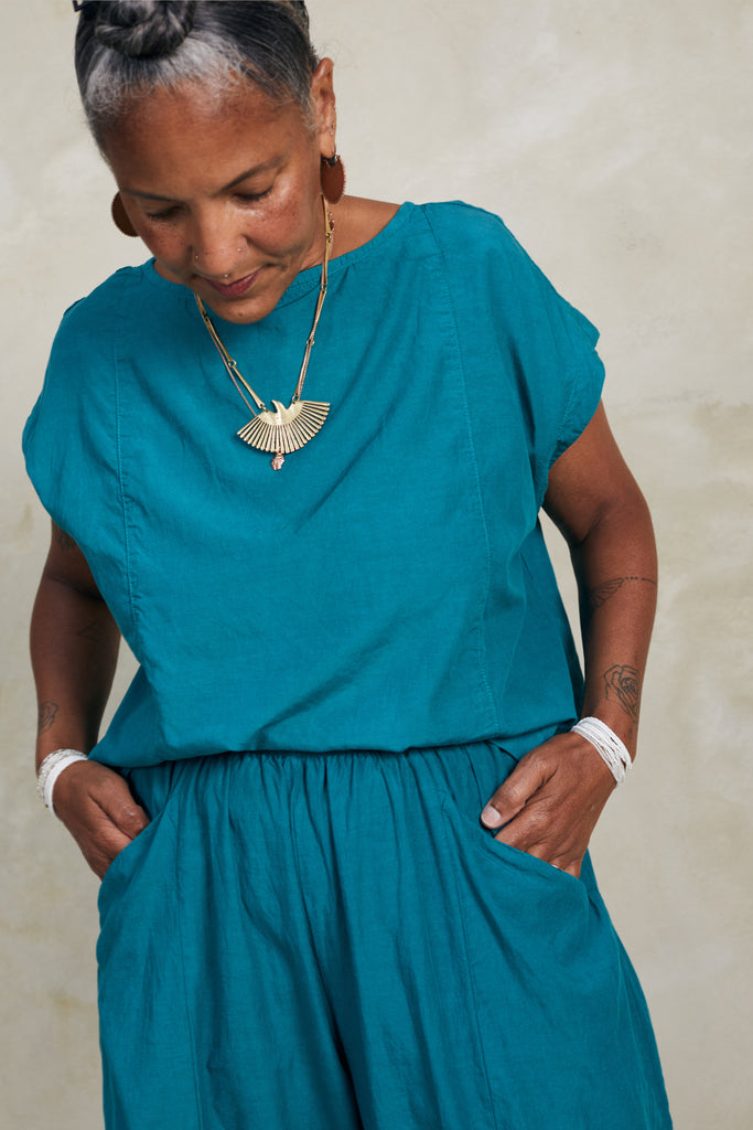 Model wearing Jones Top in Ocean and Larkin Pant in Ocean, standing with hands in pockets, in front of white background