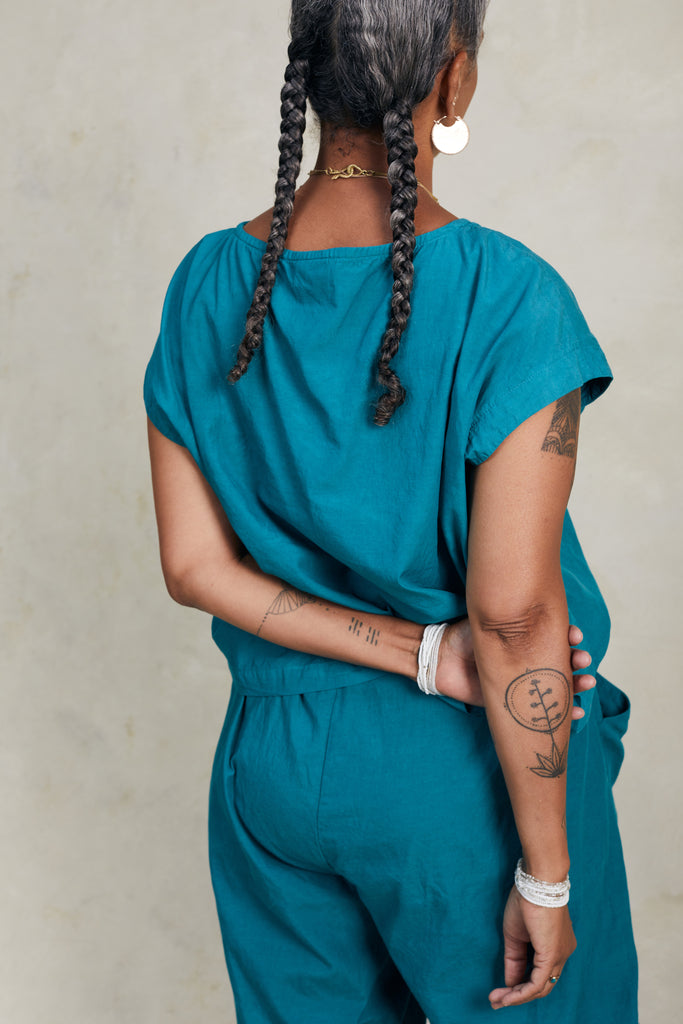 Back view of model wearing Jones Top in Ocean and Larkin Pant in Ocean, standing with arms behind back, in front of white background