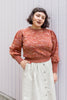 Roni Sweater in Rust Melange on model standing with hand in pocket in front of white wall