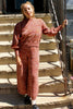 Model wearing Roni Sweater and Sofie Sweater Pant set in Rust Melange and standing on tan stone stairs