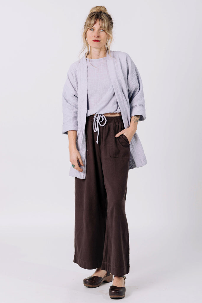 Front view of model wearing Jules Cardigan in Mist, Ayana Top in Mist, and Atlas Pant in Chocolate, standing  in front of white wall