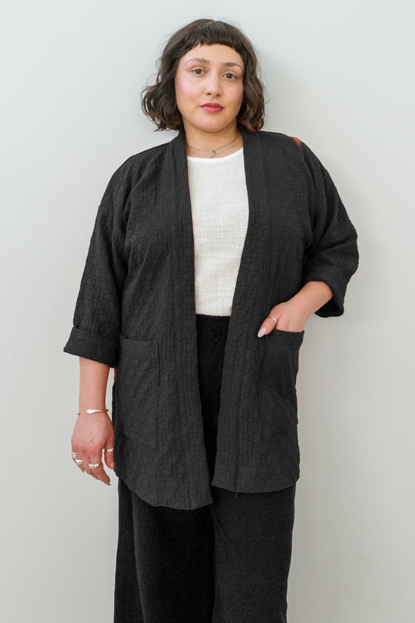 Front view of model wearing Jules Cardigan in Black, Ayana Top in White, and Atlas Pant in Black in front of white background