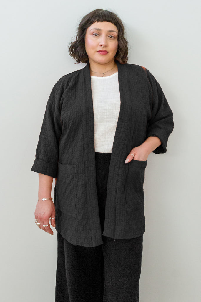 Front view of model wearing Jules Cardigan in Black, Ayana Top in White, and Atlas Pant in Black in front of white background