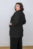 Back/side view of model wearing Jules Cardigan in Black and Atlas Pant in Black, in front of white wall