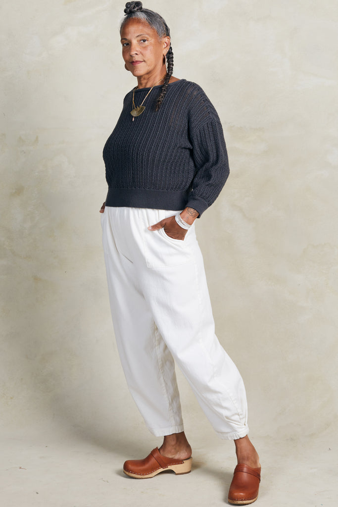 Lana Sweater in Charcoal and Cadence Pant in White on model standing with hands in pockets, in front of white background