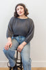 Model wearing Lana Sweater in Charcoal and light wash jeans, sitting on a stool in front of white background