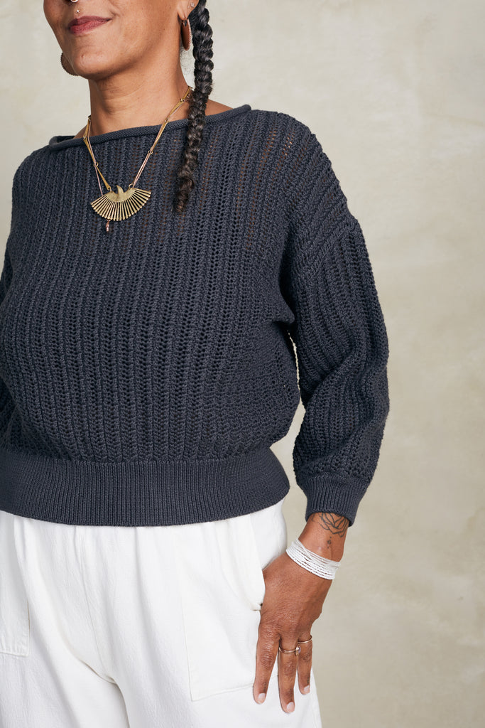 Close up of Lana Sweater in Charcoal and Cadence Pant in White on model standing in front of white background