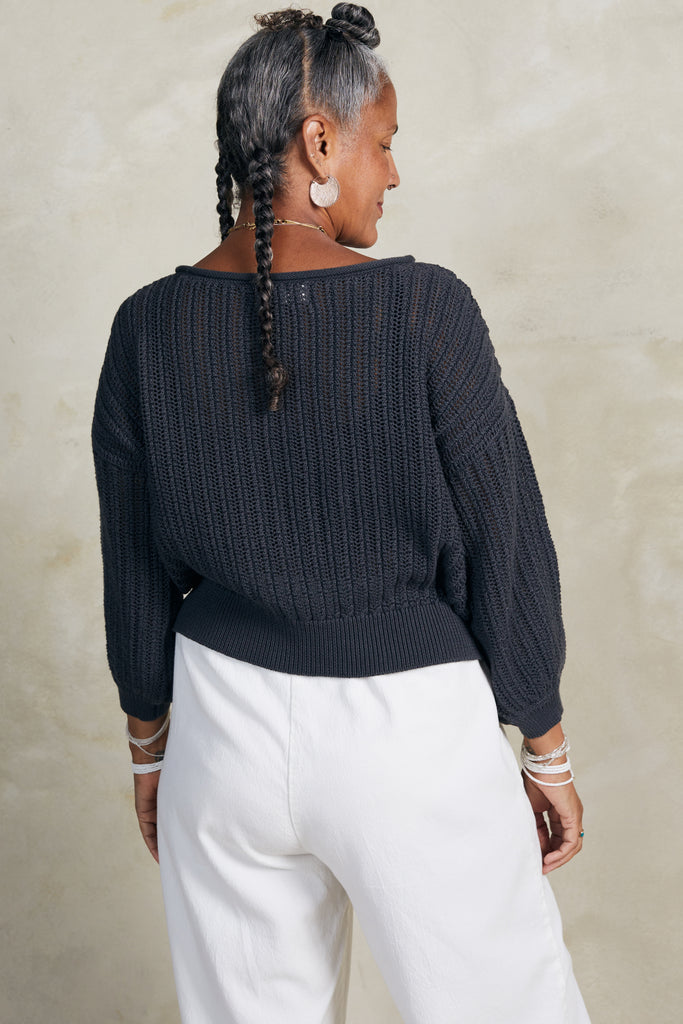 Back view of Lana Sweater in Charcoal and Cadence Pant in White on model standing in front of white background