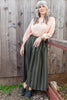 Model wearing Lana Sweater in Peach and Jessie Skirt in Mud/Black Stripe in front of wooden wall