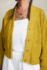 Close up of model wearing Lino Cardigan in Chartreuse and Cadence Pant in White in front of white background