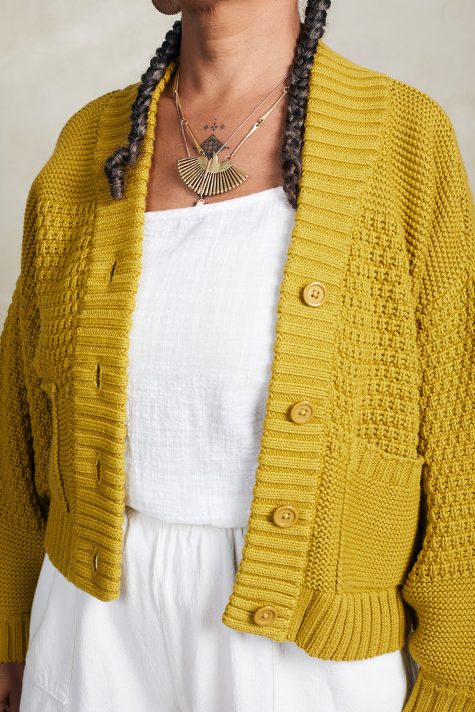 Close up of model wearing Lino Cardigan in Chartreuse and Cadence Pant in White in front of white background