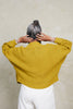 Back view of model wearing Lino Cardigan in Chartreuse and Cadence Pant in White in front of white background