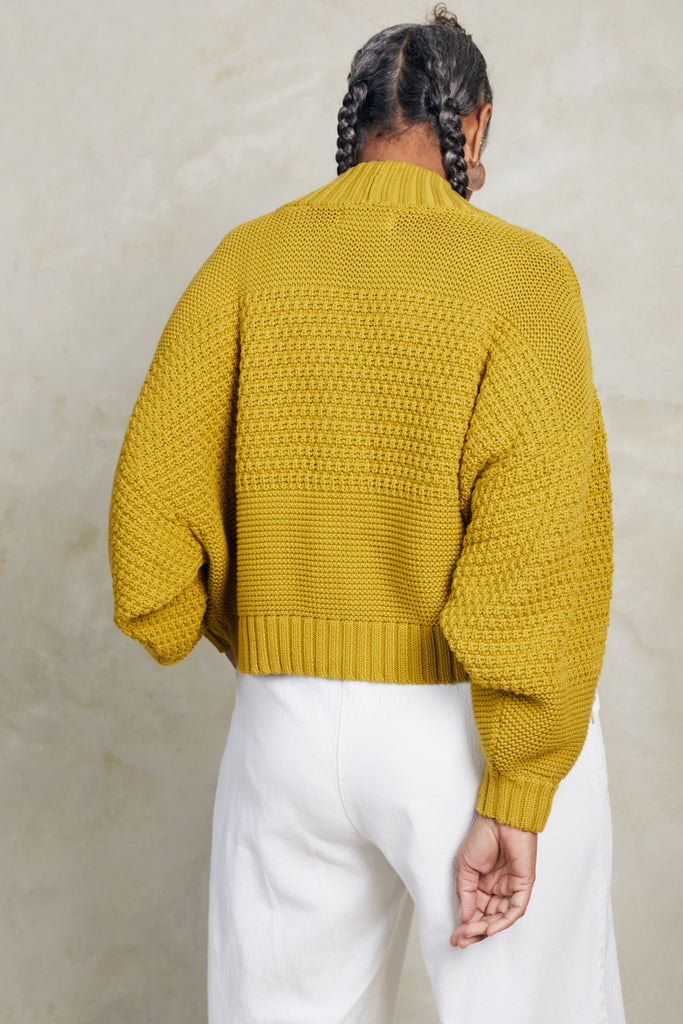 Back view of model wearing Lino Cardigan in Chartreuse and Cadence Pant in White  in front of white background