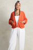 Lino Cardigan in Tomato and Cadence Pant in White on model with hands in pockets, in front of white background