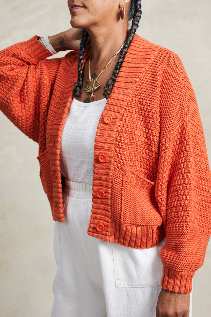 Close up of model wearing Lino Cardigan in Tomato in front of white background