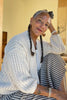 Side view of Maeva Cardigan in Biscuit paired with Fawn Skirt in Oat on sitting model in front of yellow background