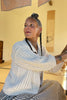 Side view of Maeva Cardigan in Biscuit on model in front of yellow background