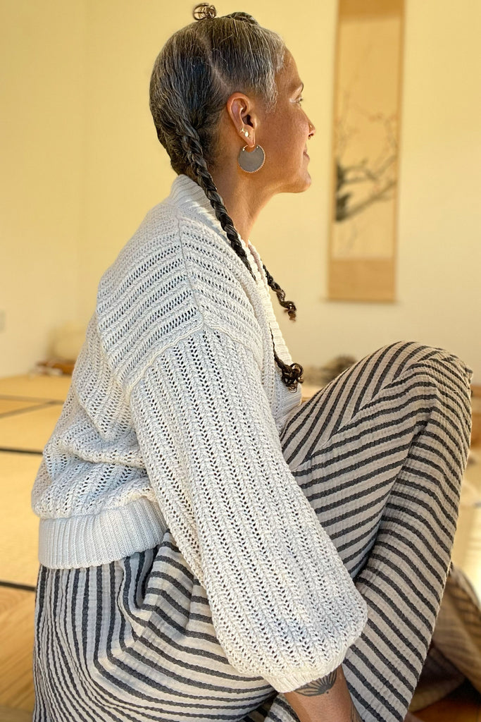 Side view of Maeva Cardigan on model in front of yellow background