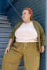 Model wearing Maeva Cardigan in Fennel, Ayana Top in Peach, and Larkin Pants in Fennel, in front of blue building with white stairs