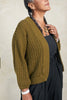 Side view of model wearing Maeva Cardigan in Fennel in front of white background