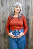 Model wearing Maisie Long Sleeve in Brick and jeans in front of wooden wall